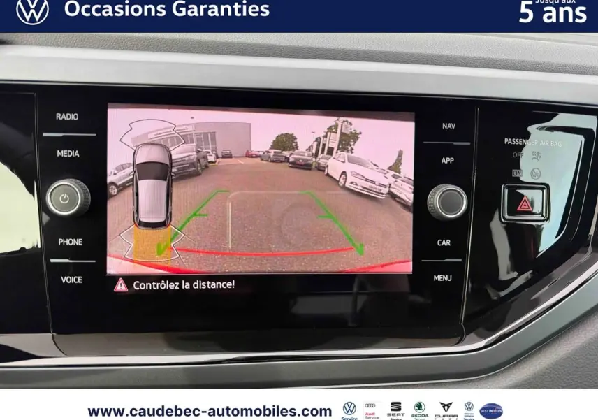 Écran tactile intérieur montrant la caméra de recul d'une Volkswagen Polo rouge vue de l'arrière en stationnement.