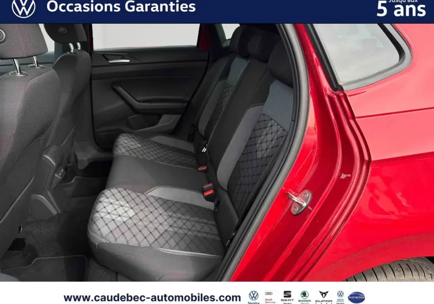 Vue côté droit arrière sur l'intérieur de la Volkswagen Polo rouge, montrant les sièges arrière en tissu gris à motifs.