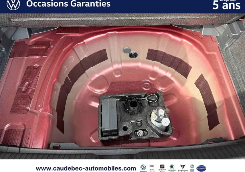 Coffre ouvert montrant la roue de secours et l'espace de rangement rouge de la Volkswagen Polo 2025.