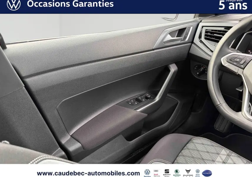 Vue intérieure côté conducteur de la Volkswagen Polo rouge 2025, avec volant cuir et commandes intégrées visibles.