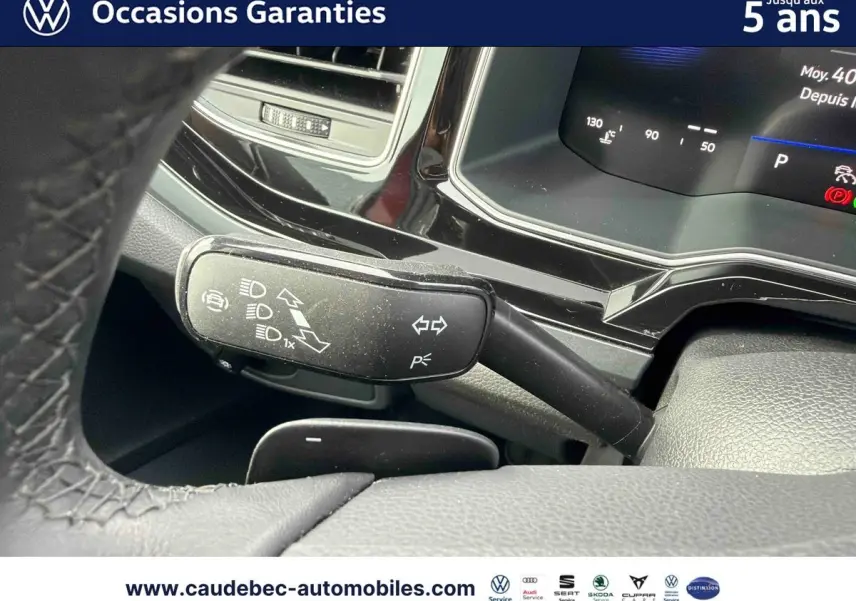 Gros plan sur la commande des clignotants et feux dans l’habitacle d’une Volkswagen Polo rouge, tableau de bord digital visible.