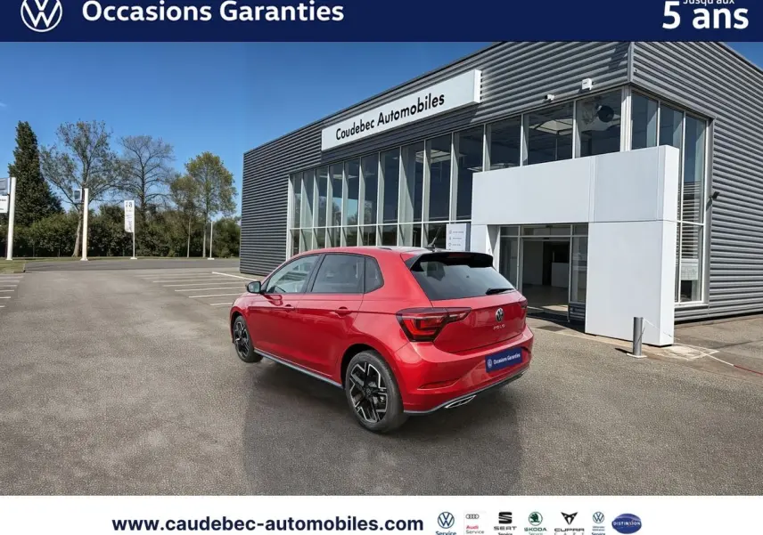 Volkswagen Polo rouge vue 3/4 arrière droit, avec jantes alliage 17 pouces, stationnée devant un bâtiment moderne.