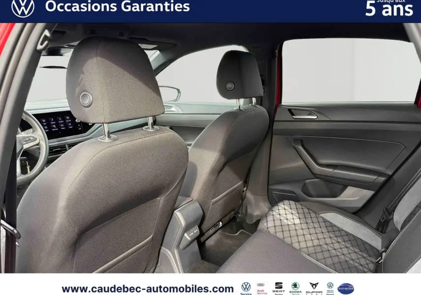 Vue intérieure arrière droite de la Volkswagen Polo rouge 2025, montrant les sièges tissu gris et les portières.