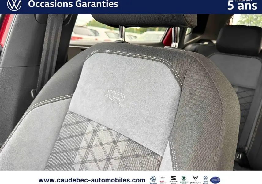 Détail du siège avant gris avec logo R brodé, intérieur de Volkswagen Polo rouge visible en arrière-plan.
