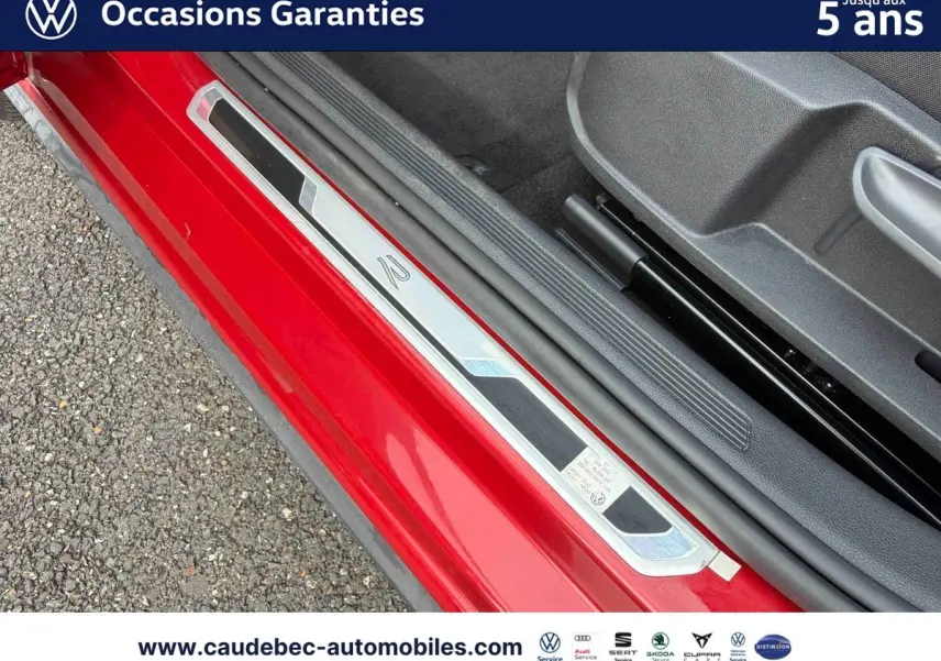 Gros plan sur la porte côté conducteur rouge d’une Volkswagen Polo avec seuil de porte R lumineux.