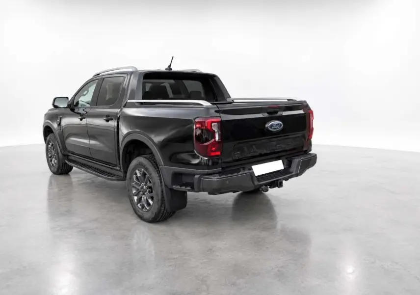 Ford Ranger 2.0 Wildtrak Plus noir agate vu 3/4 arrière droit avec arceau sport et barres de toit visibles.