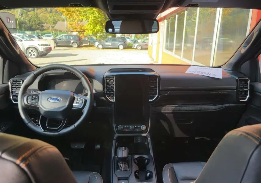 Vue intérieure avant du Ford Ranger Wildtrak 2026 avec tableau de bord noir, grand écran vertical et volant cuir multifonctions.