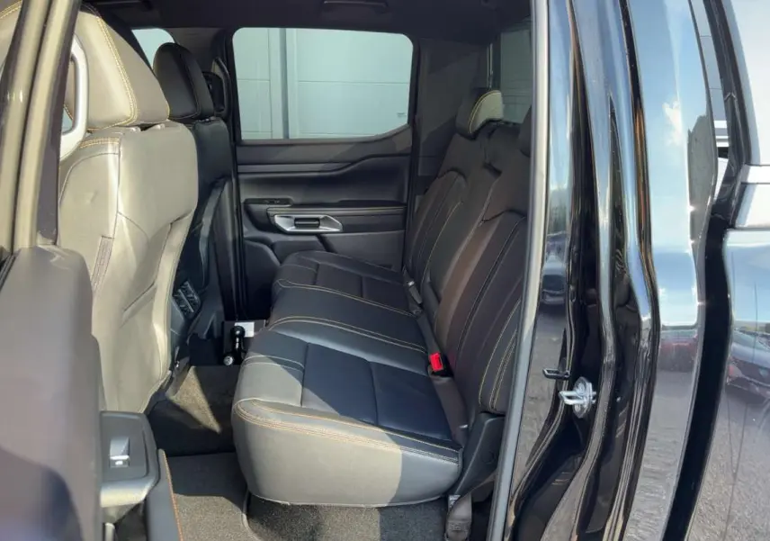 Vue latérale intérieure du Ford Ranger 2026 noir agate, montrant les sièges arrière en cuir avec surpiqûres contrastées.