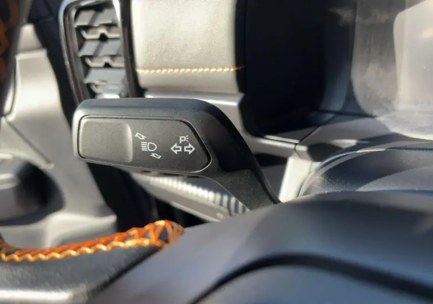 Gros plan sur la commande de clignotants du Ford Ranger Wildtrak 2026, volant cuir noir avec surpiqûres orange.