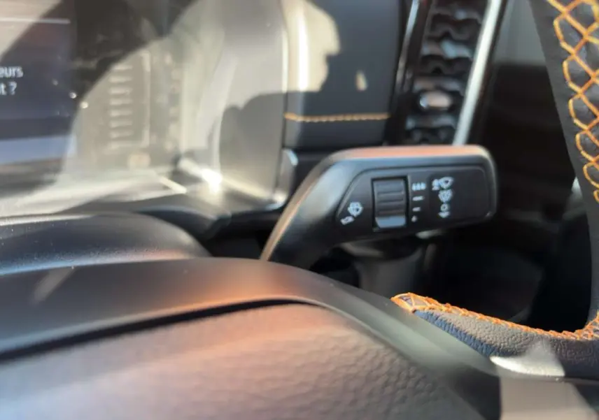 Détail intérieur du Ford Ranger Wildtrak 2026 montrant le volant cuir noir avec surpiqûres orange et commande des essuie-glaces.