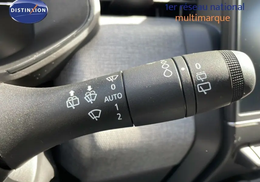 Gros plan sur la manette d’essuie-glace de la Renault Clio 2025, intérieur gris et commandes blanches visibles.