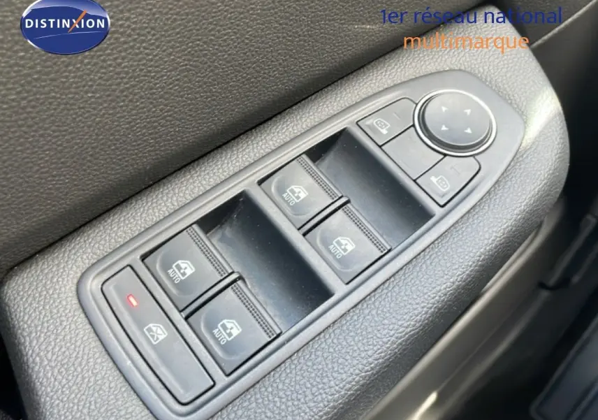 Gros plan sur les commandes des vitres électriques et rétroviseurs côté conducteur d'une Renault Clio gris schiste 2025.