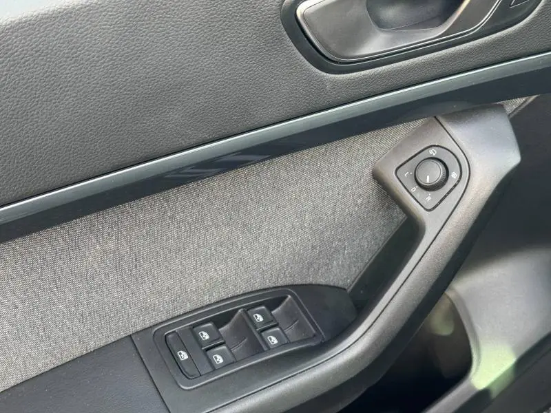 Détail de la porte intérieure côté conducteur du SEAT Ateca 2024, avec tissu gris et commandes électriques noires.