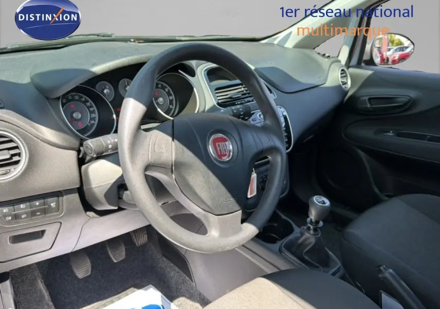 Vue intérieure côté conducteur de la Fiat Punto Street gris argent 2016, volant et levier de vitesse manuelle visibles.
