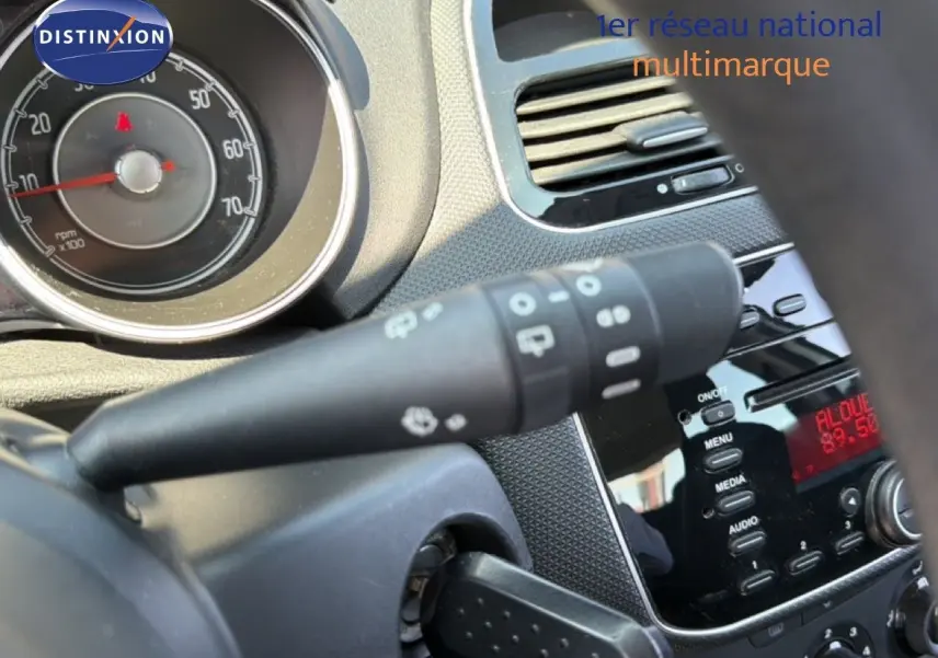 Gros plan sur le tableau de bord intérieur de la Fiat Punto gris argent, montrant les commandes et l'affichage radio.