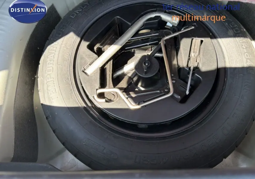 Roue de secours avec outils de changement logée dans le coffre d'une Fiat Punto Street gris argent 2016.