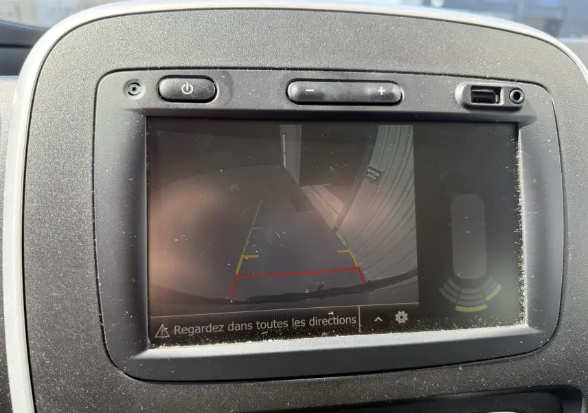 Écran de caméra de recul du Renault Trafic gris montrant les lignes de guidage colorées et l'alerte de proximité.