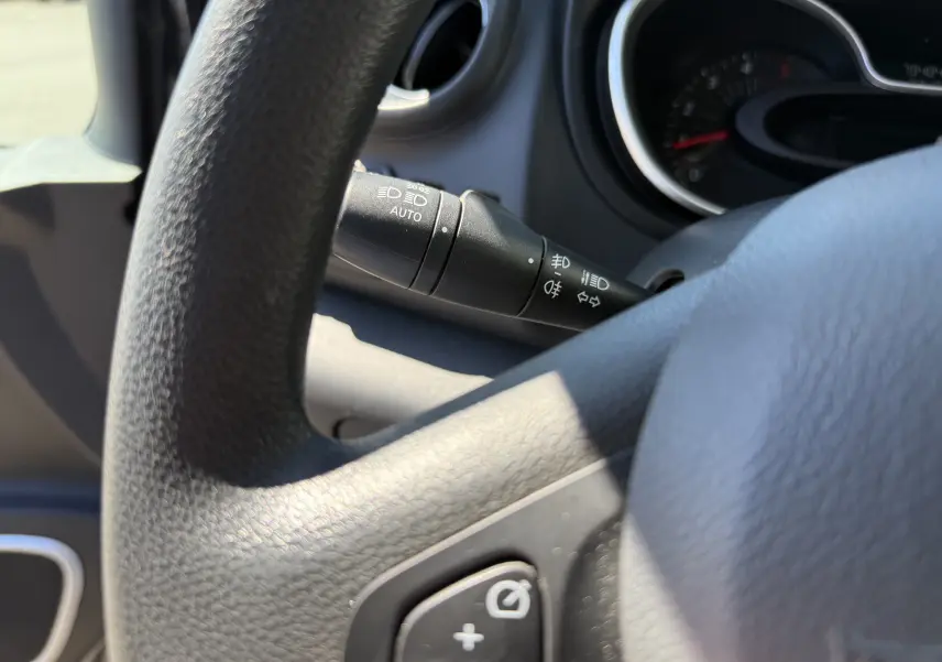 Gros plan sur le commodo d’éclairage à gauche du volant du Renault Trafic gris, avec tableau de bord en arrière-plan.