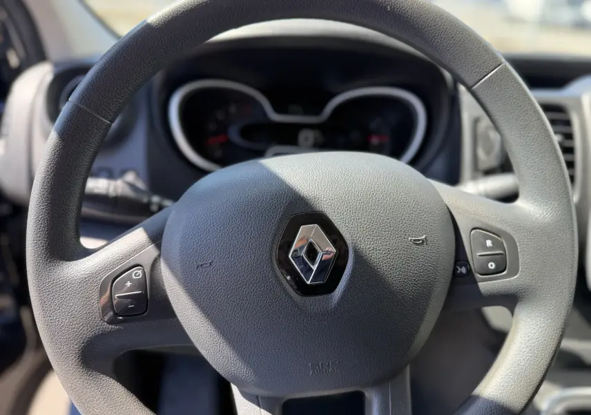 Gros plan sur le volant gris du Renault Trafic 2021 avec commandes intégrées et logo au centre.