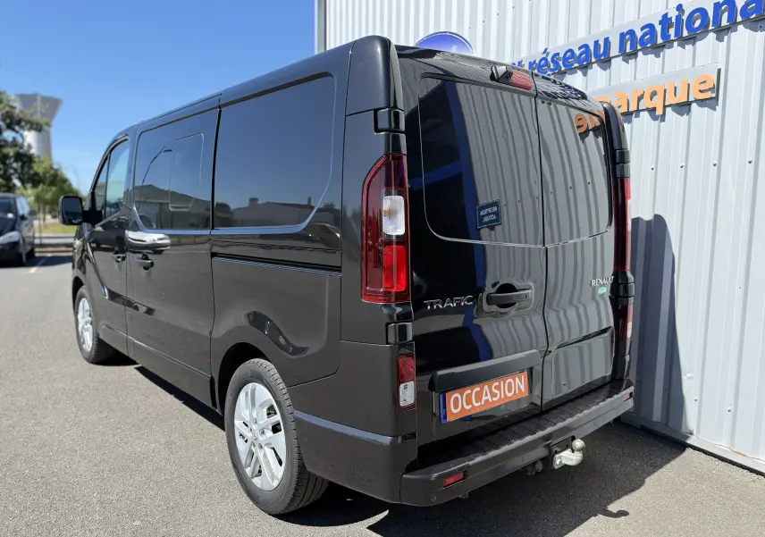 Vue 3/4 arrière droite d’un Renault Trafic cabine approfondie gris foncé, avec vitres teintées et plaque "OCCASION".