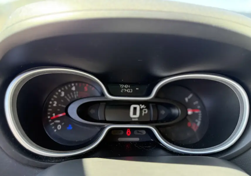 Gros plan sur le tableau de bord numérique du Renault Trafic gris, affichant le compteur de vitesse et les voyants allumés.