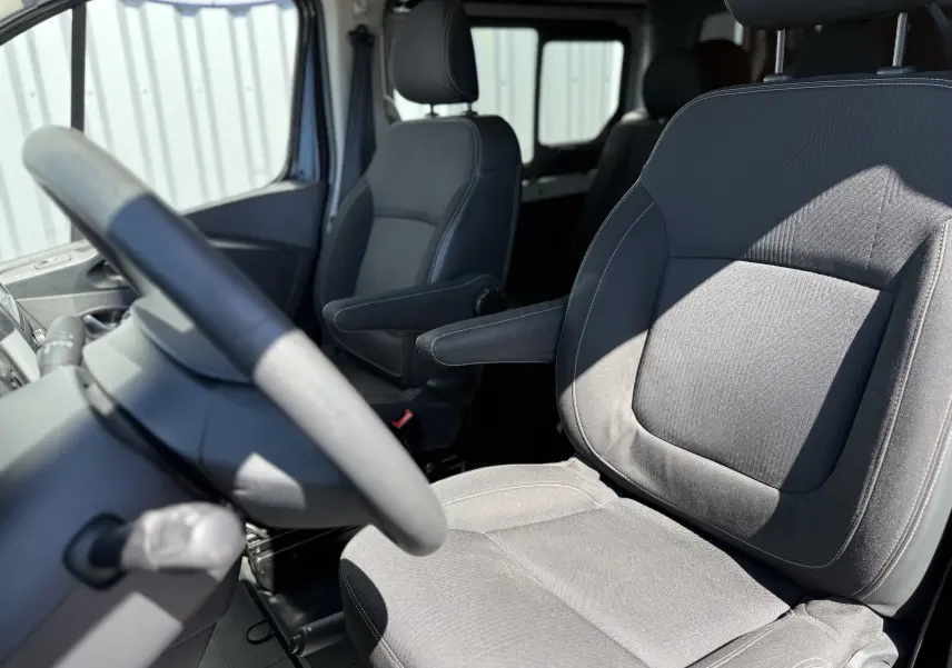 Vue intérieure rapprochée des sièges avant en tissu gris du Renault Trafic Cabine Approfondie 2021, avec accoudoirs.