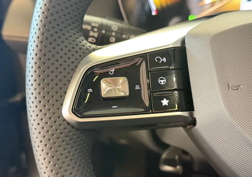 Gros plan sur les commandes gauche du volant en cuir perforé du MG ZS 2026 Candem Grey, boutons multifonctions.