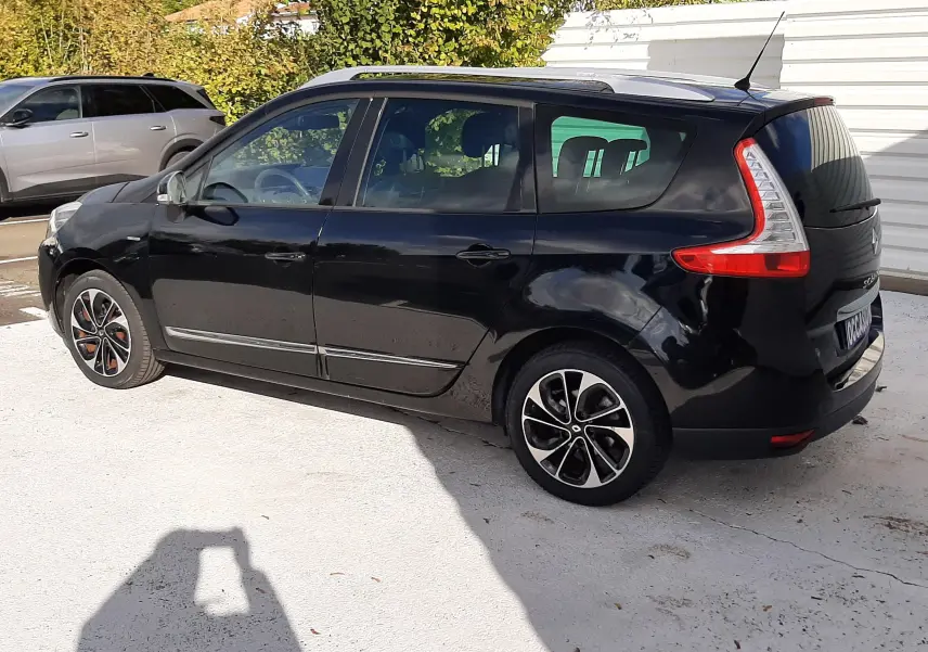 Renault Grand Scénic noir en vue de profil côté gauche, avec jantes noires et détails rouges sur les roues.
