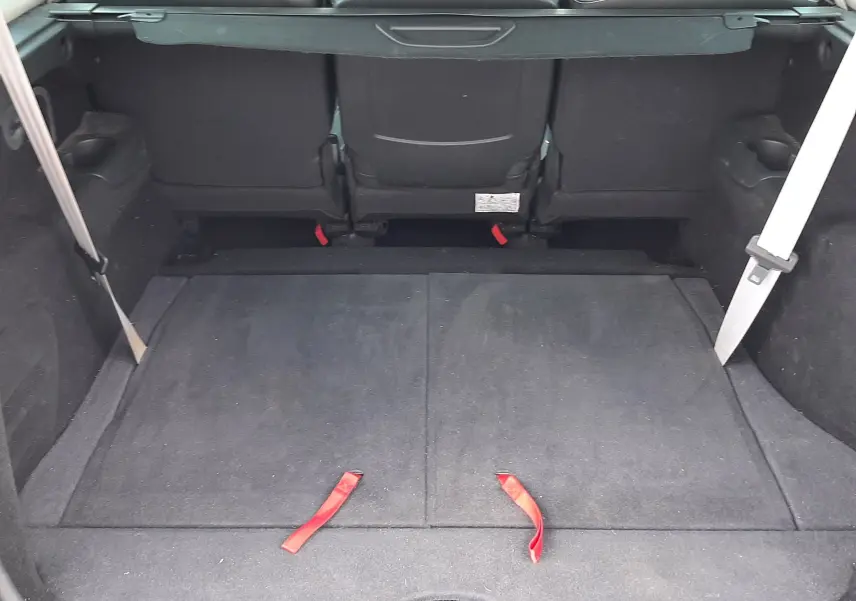 Coffre ouvert vu de l'arrière d'un Renault Grand Scenic noir, montrant la banquette arrière et l'espace de chargement.