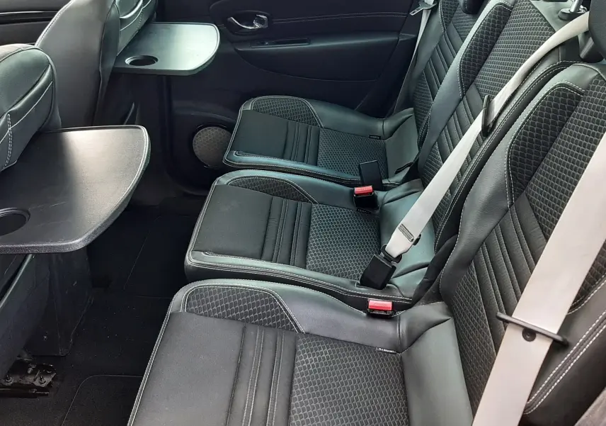 Vue intérieure côté droit des sièges arrière noirs en cuir et tissu du Renault Grand Scenic 7 places avec tablette rabattable.