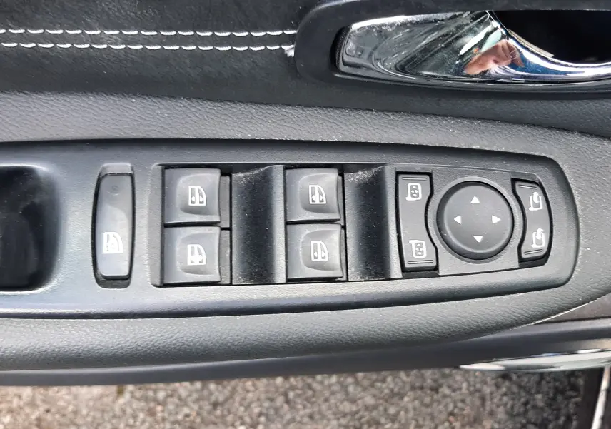 Vue rapprochée des commandes de lève-vitres et rétroviseurs sur la porte côté gauche d’un Renault Grand Scenic noir 2015.