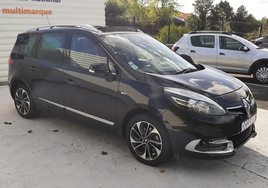 Renault Grand Scenic noir en 3/4 avant droit, avec jantes alliage et détails chromés visibles sur carrosserie.