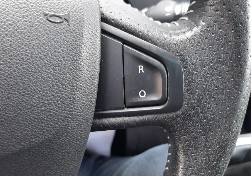 Gros plan sur le volant noir du Renault Grand Scenic 2015, mettant en valeur les boutons "R" et "O" sur la partie droite.