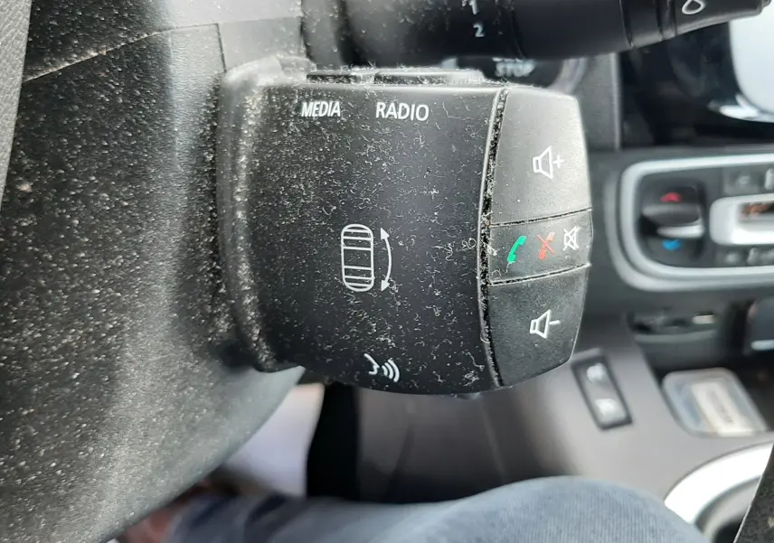 Gros plan sur les commandes au volant du Renault Grand Scenic noir, boutons médias et téléphone visibles.