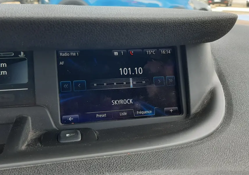 Vue intérieure du tableau de bord du Renault Grand Scenic noir, affichant la radio sur la fréquence 101.10 FM Skyrock.