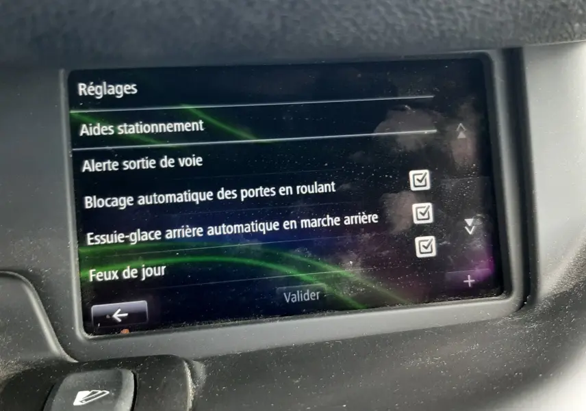 Écran tactile du tableau de bord du Renault Grand Scenic noir 2015 affichant les réglages d’aides à la conduite.