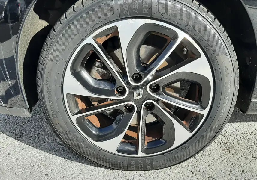 Gros plan sur la jante alliage bicolore noire et argentée d’un Renault Grand Scénic noir de 2015.