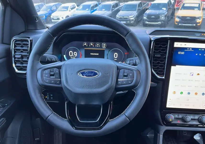 Vue intérieure centrée sur le volant cuir multifonctions du Ford Ranger 2026 avec écran tactile vertical et tableau de bord numérique.