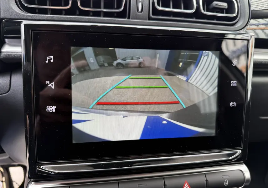 Écran tactile intérieur affichant la caméra de recul d'une Citroën C3 gris platinium avec lignes de guidage colorées.