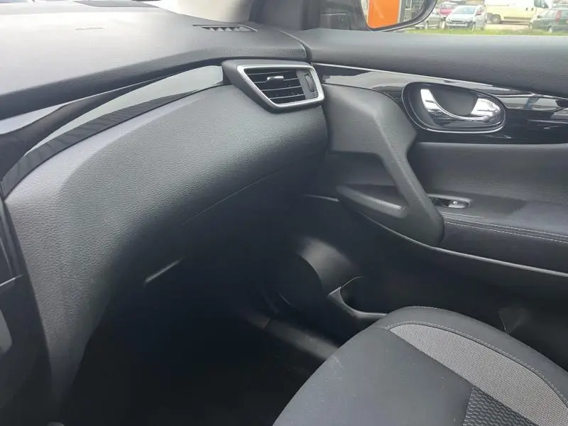 Intérieur côté passager du Nissan Qashqai 2020, avec tableau de bord et porte en tissu noir et inserts noirs laqués.