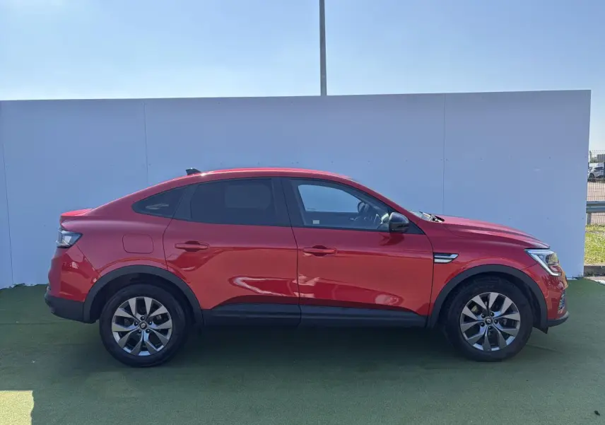 Profil droit d'un Renault Arkana rouge flamme métallisé 2025 avec jantes alliage et vitres surteintées.