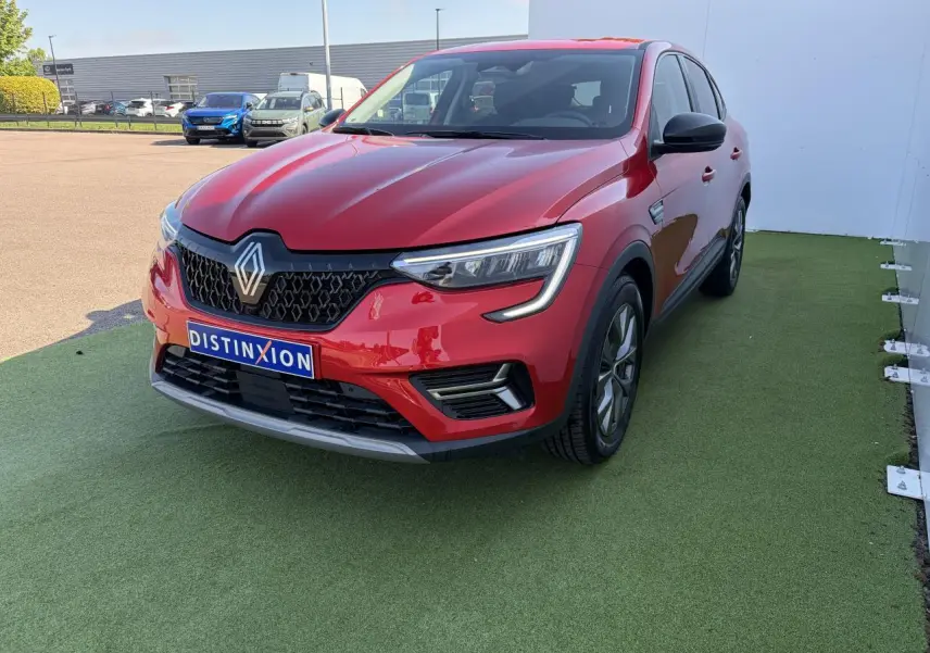 Renault Arkana rouge flamme métal vu en 3/4 avant droit, avec calandre noire et jantes alliage grises 17 pouces.