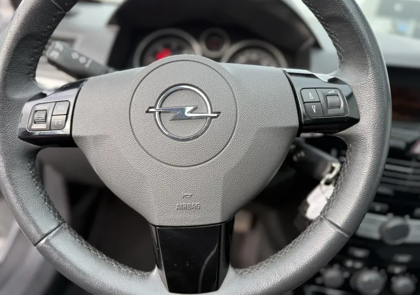 Gros plan sur le volant en cuir noir de l'Opel Astra 1.7 CDTI 110, avec commandes intégrées et logo Opel central.