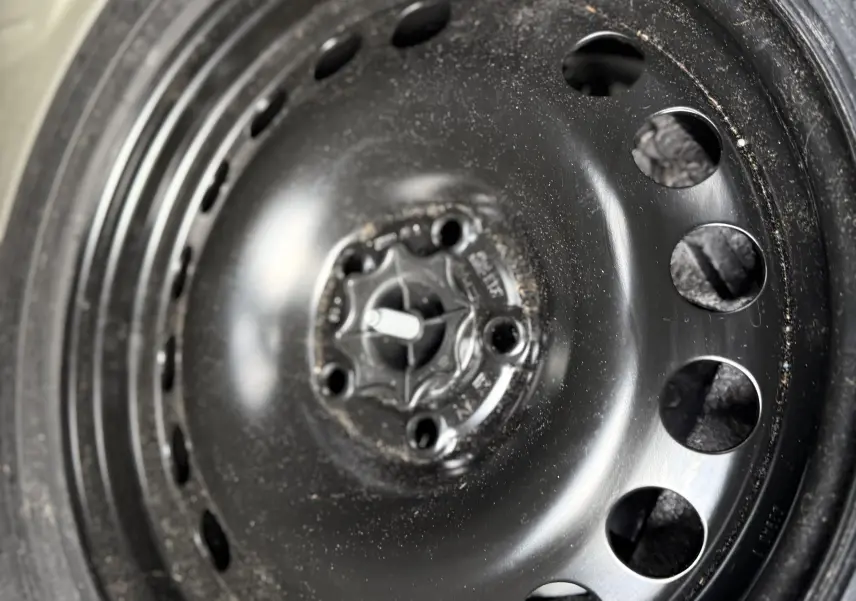 Gros plan sur la roue de secours noire en acier de l'Opel Astra gris 2010, montrant le pneu et la valve.