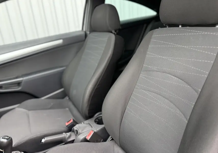 Vue intérieure côté avant droit de l’Opel Astra 2010, sièges tissu gris avec levier de vitesse manuel visible.