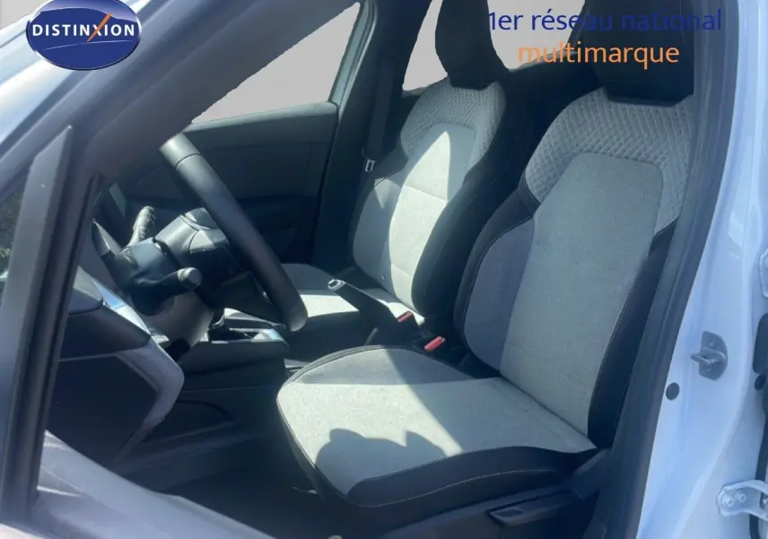 Vue intérieure côté conducteur de la Renault Clio blanche 2025, mettant en valeur les sièges tissu gris et noir.