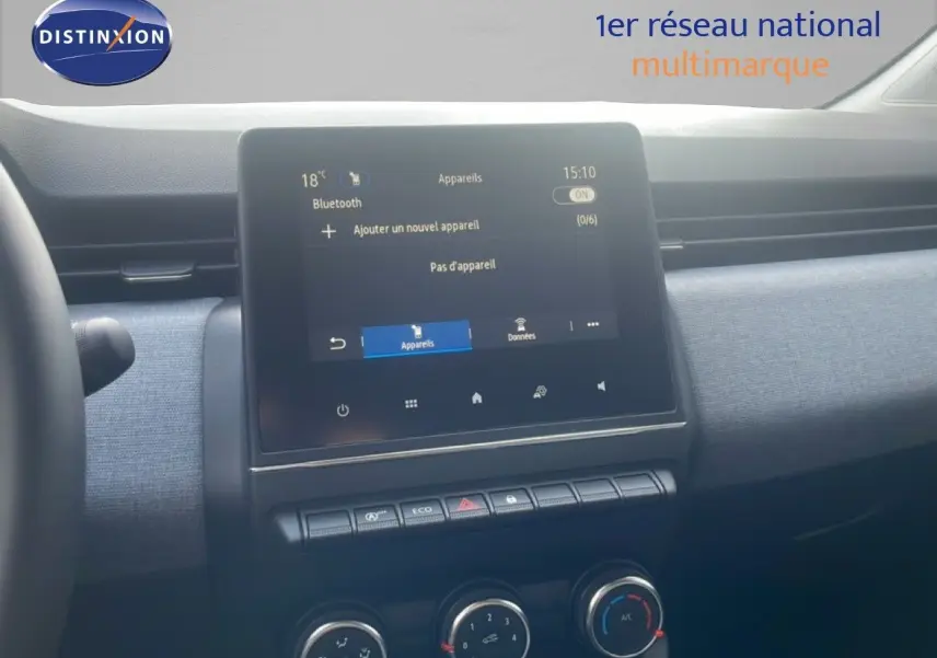 Vue intérieure centrée sur l’écran tactile et la console de la Renault Clio blanche, avec détails des commandes climatisation.