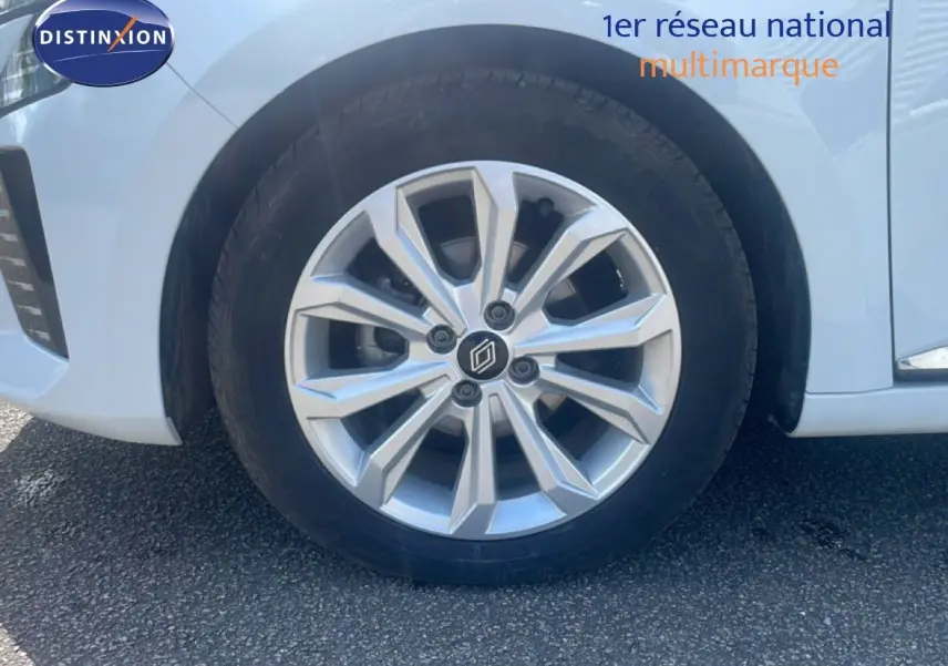 Gros plan sur la roue avant droite d’une Renault Clio blanche 2025 avec jante alliage argentée au design moderne.