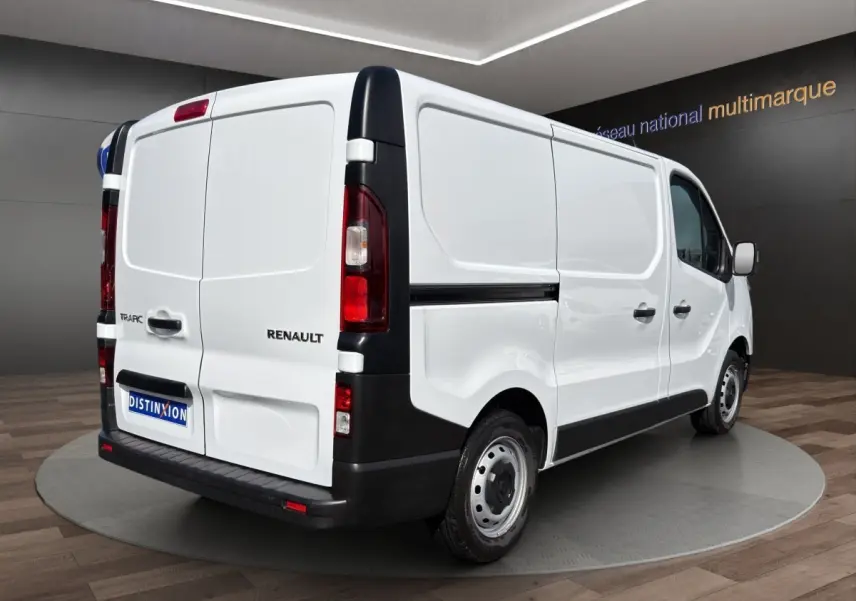 Vue 3/4 arrière droite d’un Renault Trafic Fourgon blanc avec feux arrière verticaux et pare-chocs noir.