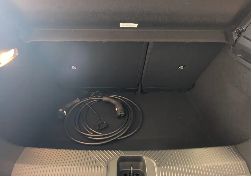 Coffre arrière ouvert de l'Alpine A290 blanc toit noir, vue plongeante sur câble de recharge électrique enroulé.
